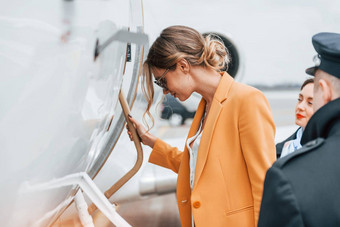 年轻的女人黄色的衣服陪同航空公司工人