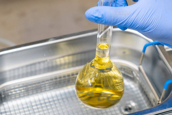 科学家蓝色的橡胶把黄色的解决方案瓶溶解提取超声波浴尿素分析临床毒理学法医分析