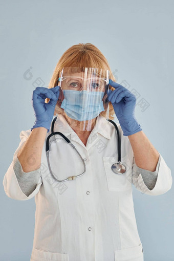 <strong>高级</strong>女医生白色外套站在室内蓝色的背景