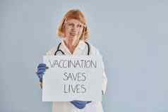 疫苗接种节省了生活横幅高级女医生白色外套站在室内