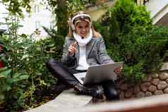 成人女人自由职业者工作移动PC在线听音乐耳机背景城市公园