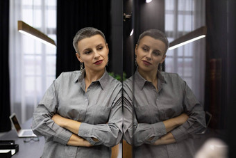 肖像成功的成熟的女商人短发型办公室反射玻璃内阁