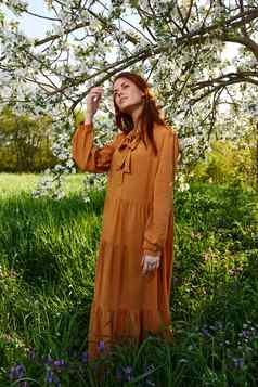 快乐适度的女人站橙色衣服开花树享受自然阳光明媚的夏天一天