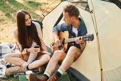 的家伙玩吉他年轻的夫妇旅行森林白天
