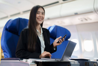 亚洲业务女人乘客坐着业务类奢侈品飞机工作智能<strong>手机</strong>移动会说话的移动PC电脑<strong>模拟</strong>空间董事会无线连接