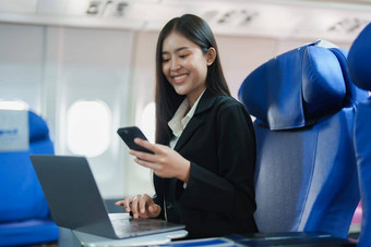 亚洲业务女人乘客坐着业务类奢侈品飞机工作智能<strong>手机</strong>移动会说话的移动PC电脑<strong>模拟</strong>空间董事会无线连接