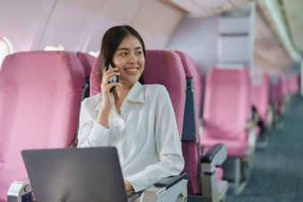 亚洲业务女人乘客坐着业务类奢侈品飞机工作聪明的电话移动会说话的视频会议旅行概念