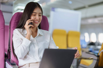亚洲业务女人乘客坐着业务类奢侈品<strong>飞机</strong>工作聪明的电话移动会说话的<strong>视频</strong>会议旅行概念