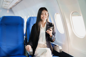 亚洲业务女人乘客坐着业务类奢侈品飞机工作聪明的电话移动会说话的视频会议旅行概念