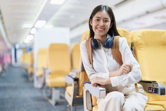 年轻的亚洲有吸引力的女人旅行<strong>飞机</strong>乘客穿耳机把手行李储物柜<strong>座位飞机</strong>