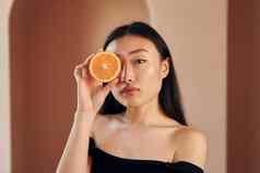 片橙色年轻的亚洲女人站在室内