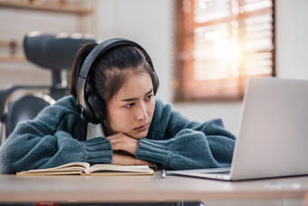 无聊年轻的亚洲女孩学生研究心烦意乱移动PC屏幕参加无聊的在线类讲座累了无聊懒惰的
