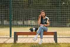 坐在体育运动场年轻的亚洲女人在户外白天