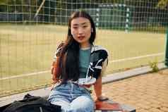坐在体育运动场年轻的亚洲女人在户外白天