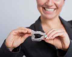 女人持有透明的塑料口警卫牙齿矫正医师的咬修正设备