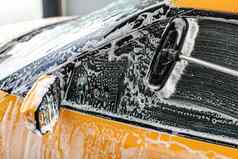 黄色的车一边窗口洗服务洗车冲叶子中风洗发水泡沫玻璃