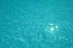 游泳池底太阳闪亮的蓝色的瓷砖行扭曲的水折射