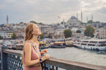 年轻的旅游女人加拉塔桥金角湾伊斯坦布尔全景城市景观著名的旅游目的地横跨博斯普鲁斯海峡海峡通道旅行景观博斯普鲁斯海峡火鸡欧洲亚洲