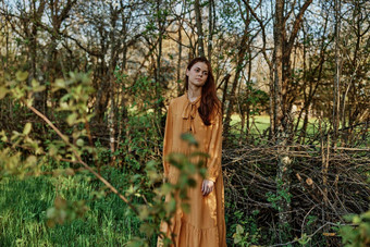 美丽的纤细的女人长头发走阴影树穿着长橙色衣服享受天气周末主题隐私自然