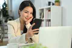 美丽的亚洲女人智能手机首页办公室桌子上沟通技术业务生活方式概念