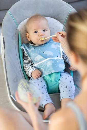 妈妈。勺子喂养婴儿男孩婴儿孩子婴儿椅子<strong>水果泥</strong>婴儿固体食物介绍概念