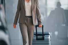 正式的衣服女人行李站在室内概念旅游