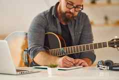 练习写歌技能男人。休闲衣服声吉他在室内
