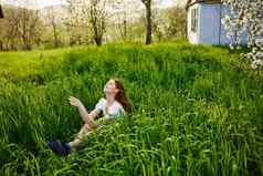 可爱的女人坐在高草背景房子