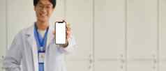 医生穿白色统一的显示智能手机空白屏幕广告远程医疗在线应用程序概念