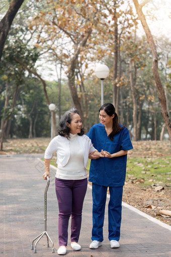 护士帮助上了年纪的女人沃克护士持有手上了年纪的女人走公园设施