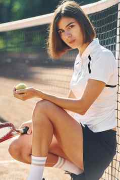 坐着持有球拍女网球球员法院白天