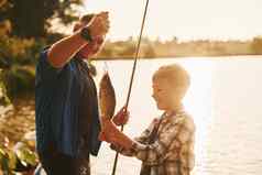 显示抓父亲儿子钓鱼在户外夏季