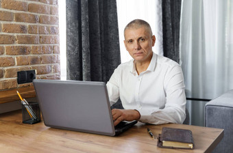 肖像中间岁的业务男人。工作首页移动PC