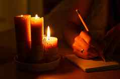 女人使笔记笔记本黑暗房间燃烧蜡烛
