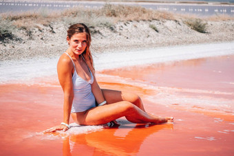 年轻的女人长头发粉红色的咸湖晶体盐极咸粉红色的湖彩色的微藻水晶盐口供水疗中心美健康护理概念