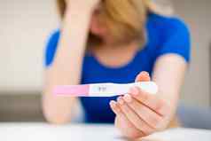 单伤心女人持有积极的怀孕测试