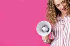 年轻的女人持有扩音器手表达情绪赢家孤立的粉红色的背景