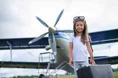 女孩飞行员的服装携带复古的手提箱走机场孩子他眼镜旅行飞机