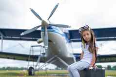 女孩飞行员的服装坐在手提箱背景飞机螺旋桨孩子梦想飞行天空