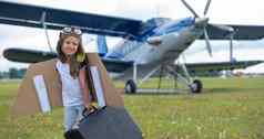 女孩飞行员的服装持有复古的手提箱场飞机螺旋桨孩子他眼镜纸板翅膀梦想飞行天空