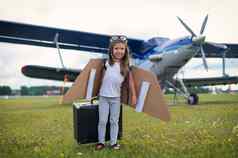 女孩飞行员的服装坐在复古的手提箱机场等待离开飞行孩子他眼镜旅行飞机