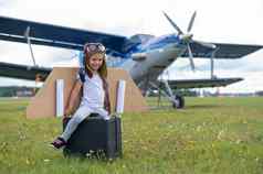 女孩飞行员的服装持有复古的手提箱场飞机螺旋桨孩子他眼镜纸板翅膀梦想飞行天空