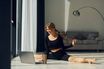 移动PC女人运动型衣服瑜伽在室内
