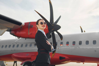 年轻的空姐正式的黑色的衣服站在户外飞机