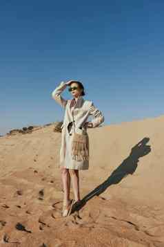 女人站金沙袋时尚的夹克眼镜清晰的天空