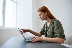 红发女人打字移动PC坐着表格办公室窗口工作完整的时间