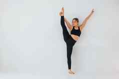 练习腿年轻的女人运动型衣服体操在室内