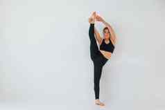 练习腿年轻的女人运动型衣服体操在室内