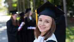 集团快乐学生毕业礼服在户外年轻的女孩快乐收到文凭