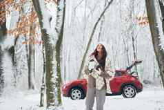 走森林美丽的年轻的女人在户外红色的汽车冬天时间